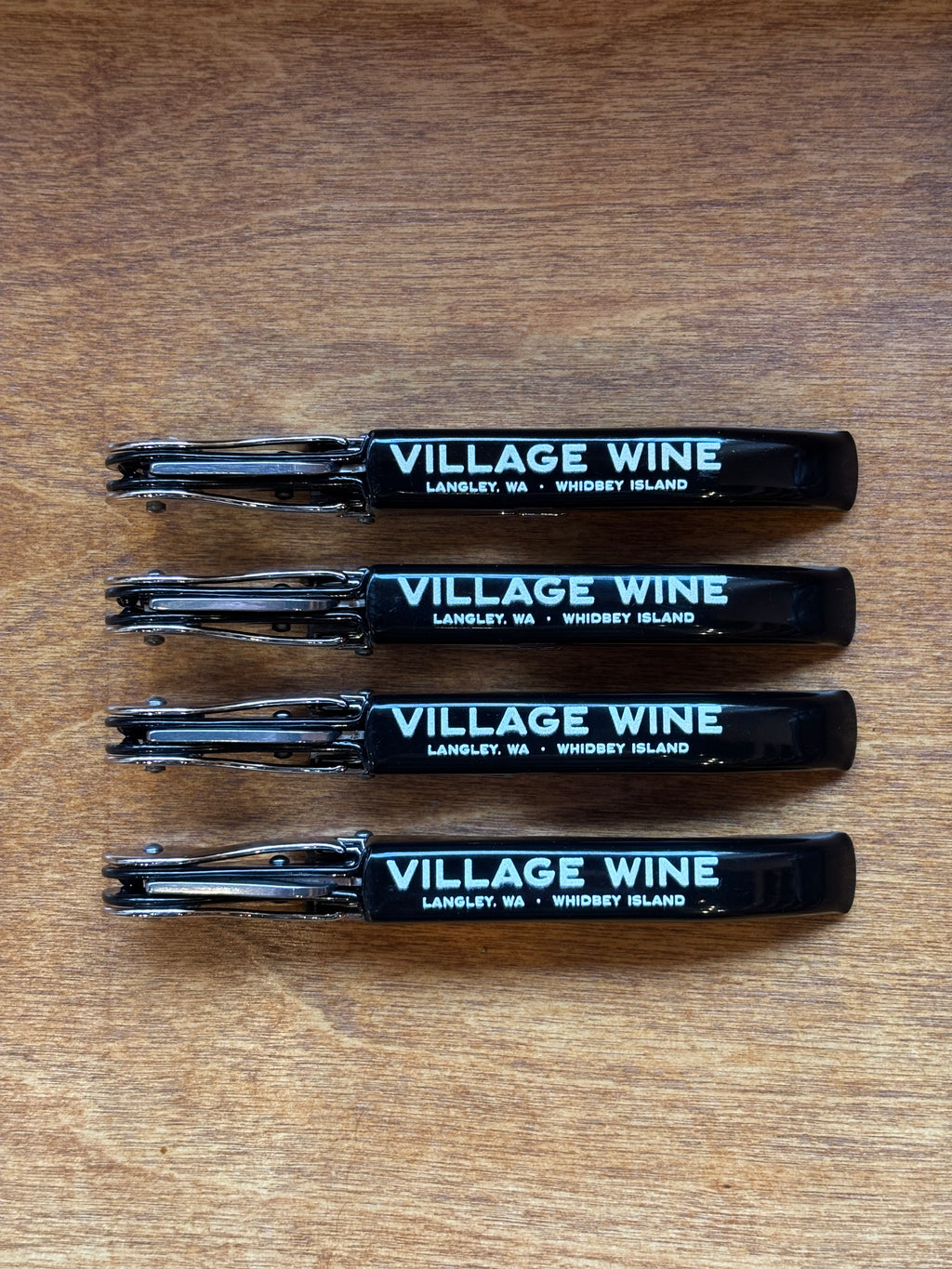 Four Village Wine bottle openers on a wooden surface